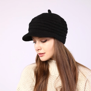 Close-up of black ribbed knit visor beanie with thick warm texture and short brim