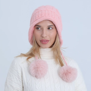 Dettaglio della maglia del berretto invernale rosa con morbidi pompon in pelliccia