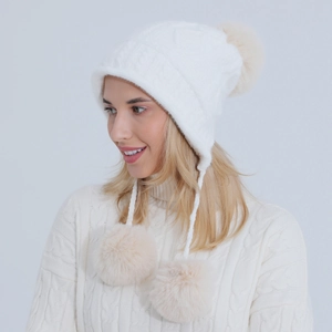 Dettaglio della trama a maglia di un berretto invernale bianco con pompon beige morbidi