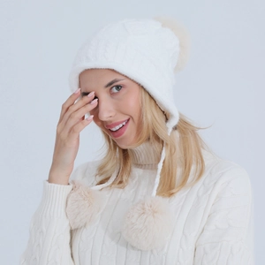 Dettagli della maglia del berretto bianco con paraorecchie, pompon e cordini intrecciati
