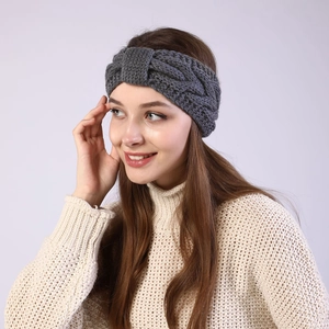 Detail of dark grey knit headband with twist knot pattern worn by model in winter
