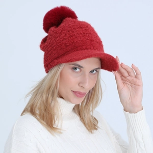 Close-up of red cable knit hat featuring a thick brim and fluffy pom-pom detail
