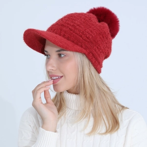 Detailed close-up of a red winter knit baseball cap with a soft faux fur pompom detail