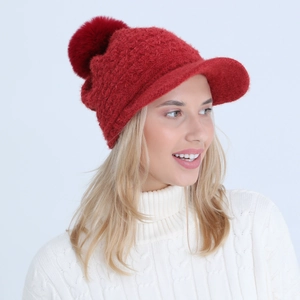 Close-up of red knit peak cap with large faux fur pompom and soft mohair texture