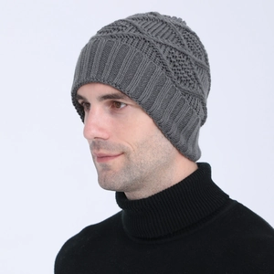 Detailed close-up of dark grey knitted beanie with diamond pattern on a model