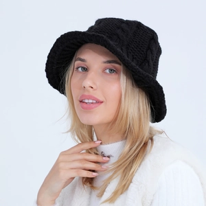Detail of black cable knit bucket hat showing thick textured weave and wavy brim