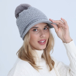 Detail of grey cable knit visor beanie with large pompom decoration and soft lining
