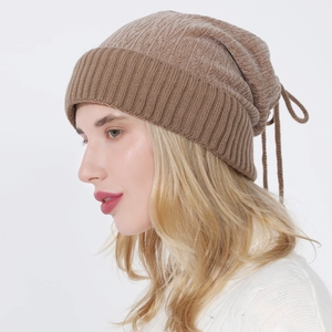 Detail of light brown ribbed knit beanie featuring an adjustable double drawstring closure