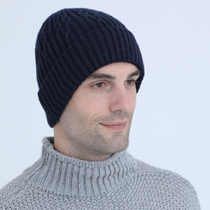 Detail of navy blue cable-knit beanie featuring thick wool texture and ribbed fold-over cuff