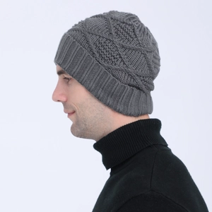 Detail of grey knitted beanie showing thick diamond pattern texture and ribbed cuff