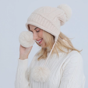 Dettaglio del cappello in maglia di ciniglia crema con pompon e paraorecchie invernali