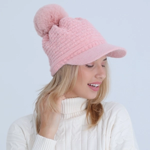 Detail view of pink knitted visor beanie with large pom-pom and thick cable knit texture