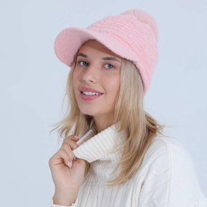 Detailed knit texture of pink winter hat with soft pompom and warm ear protection