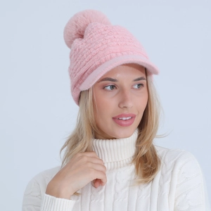 Close-up of pink knit winter hat featuring a honeycomb texture and faux fur pom-pom