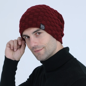 Detail of burgundy knit beanie featuring a square texture and black bear patch accent