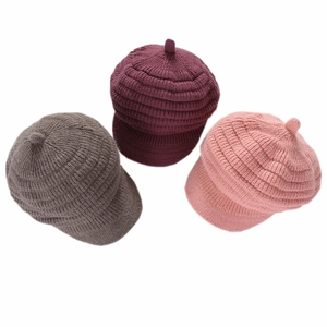 Close-up of thick striped knit texture on winter peak beanies in three warm colors