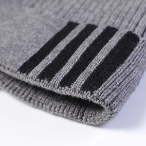 Detail of grey rib-knit beanie with black contrast stripes and soft wool texture