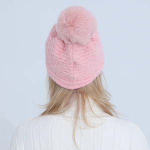 Detail of pink knitted beanie with a large fluffy pom-pom and warm texture