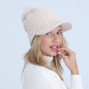 Detail of cable knit pattern and faux fur pom-pom on beige winter brimmed hat