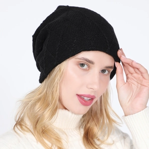 Detail of black knit beanie with diamond pattern texture on a model wearing white sweater