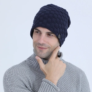 Close-up of deep blue knitted beanie with 3D textured pattern and side logo label