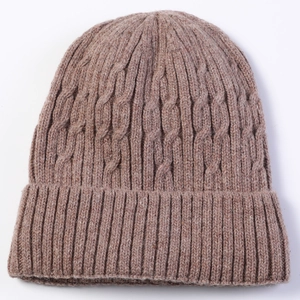 Macro detail of men's cable knit beanie featuring thick wool texture and ribbed cuff