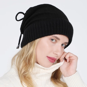 Detail of black knit beanie featuring adjustable drawstring and sleek metal pendants