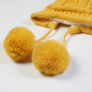 Texture a maglia dettagliata di un cappello invernale giallo con fodera in pile e pompon