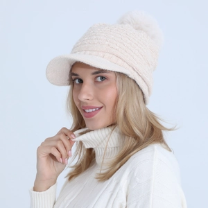 Close-up of cable knit pattern and soft faux fur pompom on cream winter beanie hat