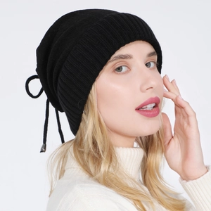 Detail showing black slouchy knit beanie with adjustable drawstring and silver buckle