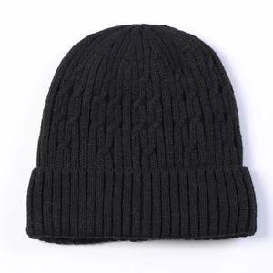 Detail of black cable knit beanie with thick ribbed cuff and fleece lining texture