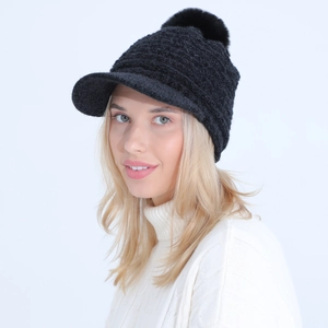 Detail of black winter knit hat with visor and large pom-pom on white background