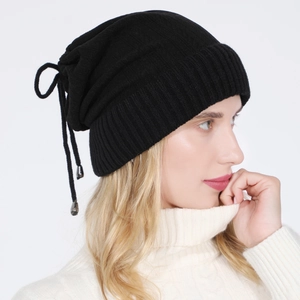 Detail of black ribbed knit beanie with adjustable drawstring and metal charm accents