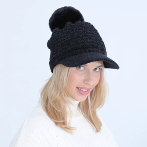 Close-up of black knit peak cap with large pom-pom and textured boucle yarn detail
