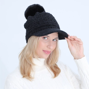 Detail of black thick knit beanie with pom-pom and brim on a model in winter sweater