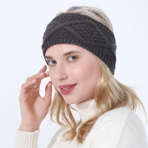 Detail of dark grey cable knit headband with twisted design on female model in sweater