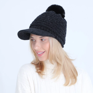 Detail of black knit beanie with brim and faux fur pom-pom shown on a model