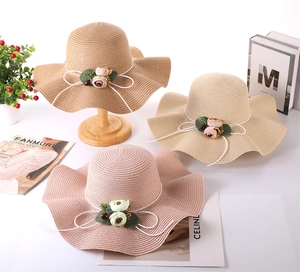 Detailed view of woven straw sun hats with floral decor and elegant wavy brims
