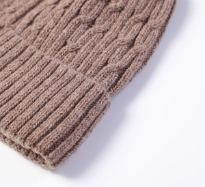 Close-up of brown cable knit beanie showing thick wool texture and ribbed cuff detail