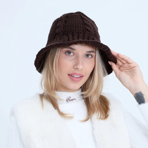 Detail of dark brown knit bucket hat with textured cable pattern on female model