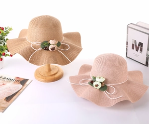 Close-up of woven straw sun hats featuring delicate floral clusters and bow detail