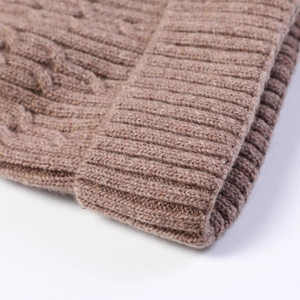Detail of brown cable knit beanie showing thick wool texture and ribbed edge
