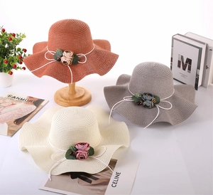 Detail of wide brim straw sun hats with floral decor and ribbon in multiple colors