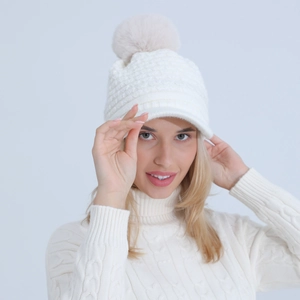 Detailed knit texture of white winter hat with pompom and matching cable sweater