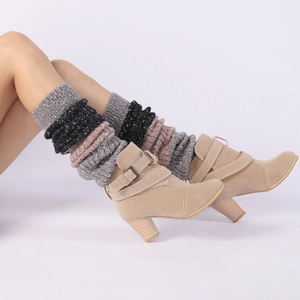 Detail of colorful knitted leg warmers paired with stylish beige suede ankle boots