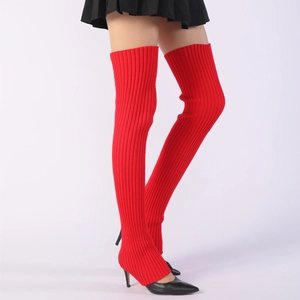 Macro detail of red ribbed knit thigh-high leg warmers paired with black stiletto heels