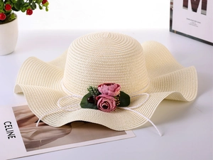 Detail of wide brim straw sun hat featuring decorative pink flowers and green leaves