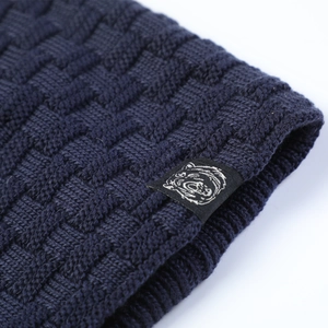 Macro shot of navy blue knit beanie fabric texture with bear logo square woven label
