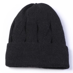 Detailed view of black cable-knit beanie featuring thick wool texture and ribbed cuff