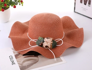 Close-up of woven straw texture with floral accents on a wavy wide brim sun hat